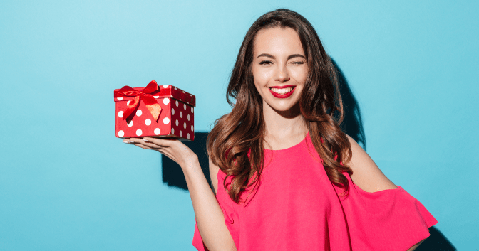 gifts for your event planner - woman winking and holding a wrapped gift
