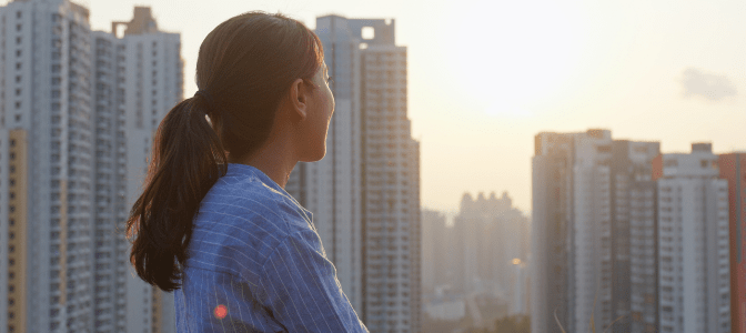woman staring out at city landscape at sunset